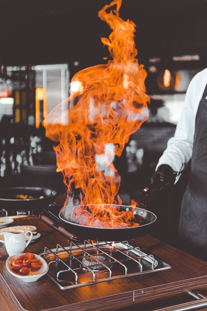 Chef skillfully handles a dramatic flame while cooking in a professional kitchen.